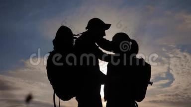 幸福的家庭游客剪影在日落拥抱接吻。 团队合作旅游概念。 男女生活方式夫妻
